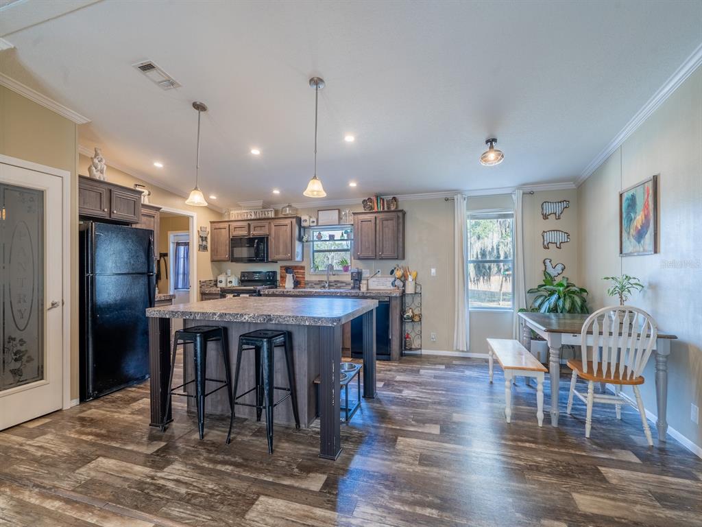 22457 Northeast 130th Court Road Fort McCoy, FL 32134 - Photo 13 of 43 a open kitchen with stainless steel appliances granite countertop a dining table chairs stove refrigerator and cabinets