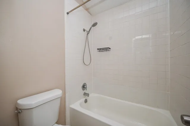 a white bath tub sitting next to a white toilet and a shower