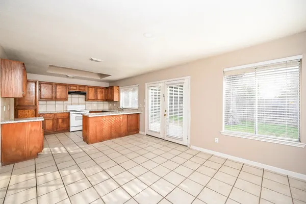 a large kitchen with stainless steel appliances granite countertop a stove a sink dishwasher and white cabinets next to a window
