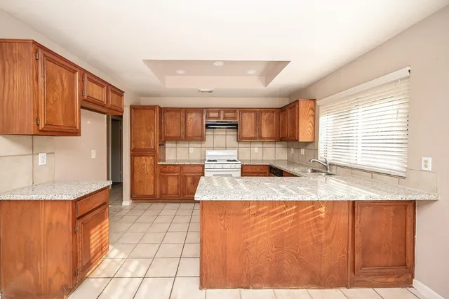 a large kitchen with granite countertop a sink and a refrigerator