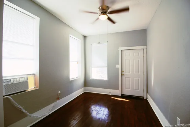 a view of empty room with wooden floor and fan