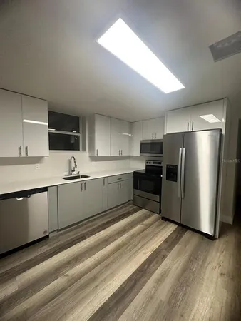a large kitchen with a refrigerator sink and white cabinets
