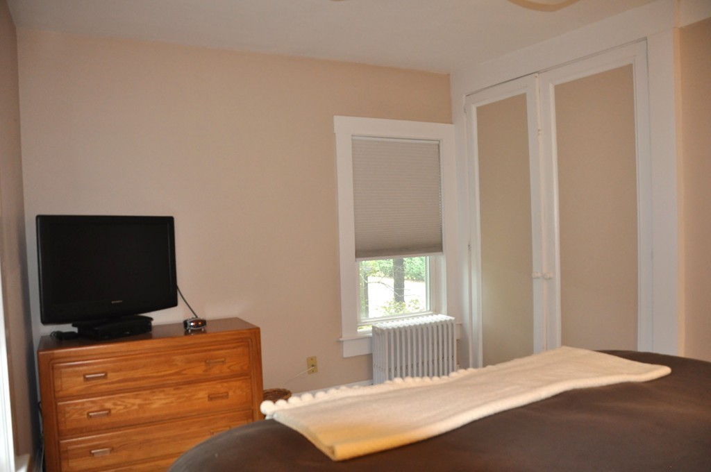 86 Spring Street, Unit B Stoneham, MA 02180 - Photo 10 of 17 a bedroom with a bed and a flat screen tv