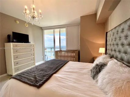 a bedroom with a large bed and a flat tv screen