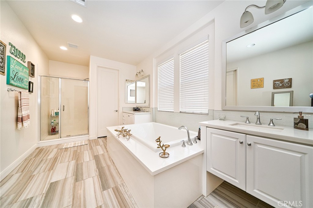 11568 Lark Drive Rancho Cucamonga, CA 91701 - Photo 15 of 20 a bathroom with a sink a bathtub a mirror a vanity and a shower