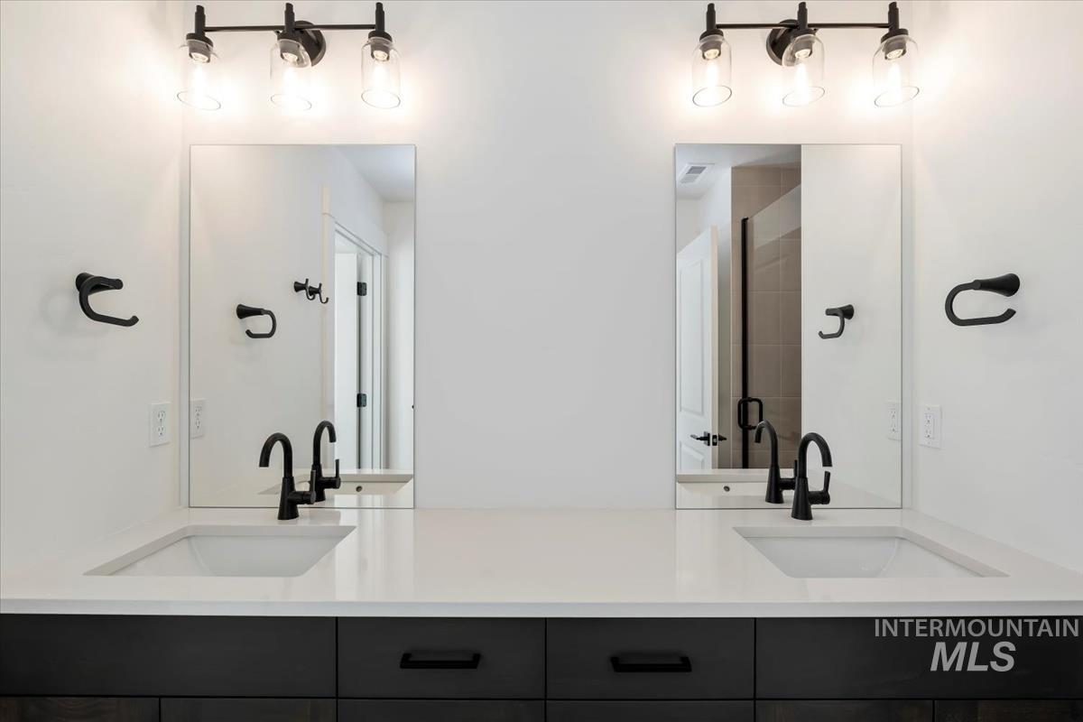 752 South Calhoun Lane Star, ID 83669 - Photo 18 of 45 Dual vanity featuring a light countertop, integrated sinks, dark cabinetry, and matte black fixtures