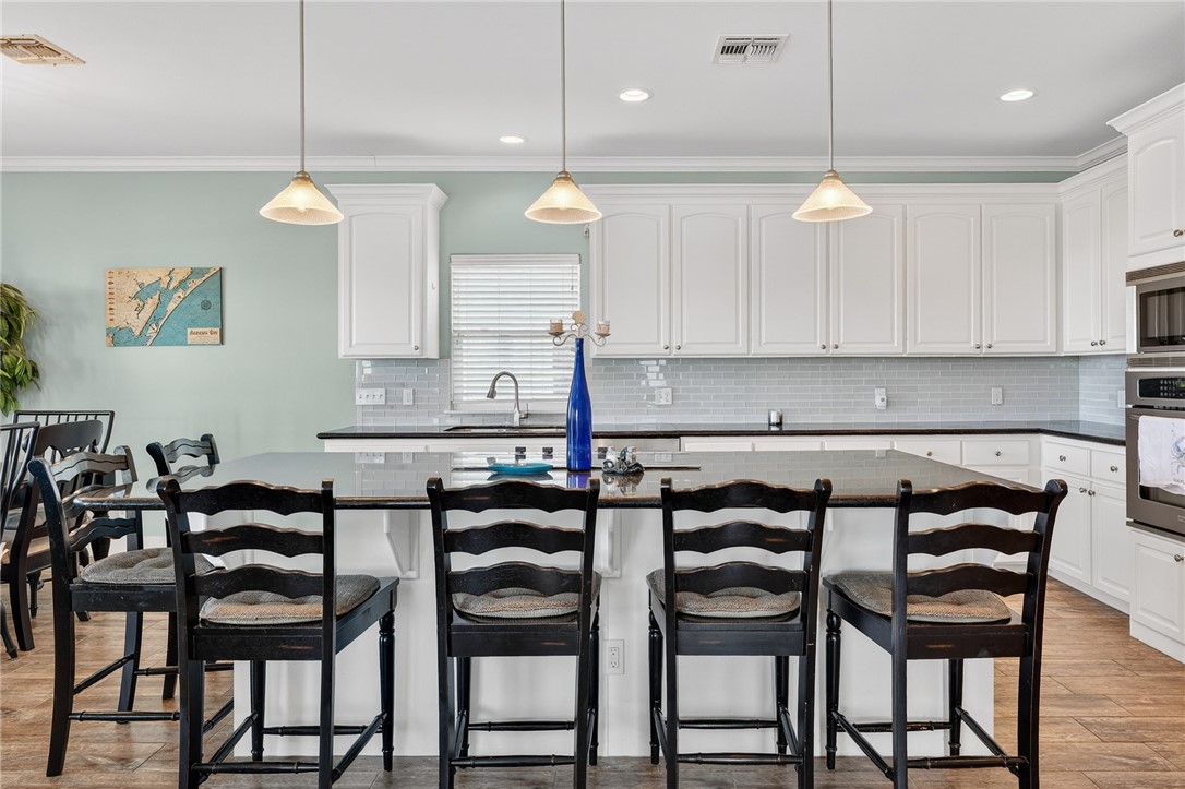 838 Rattlesnake Point Road Rockport, TX 78382 - Photo 15 of 40 a kitchen with a dining table chairs and white cabinets
