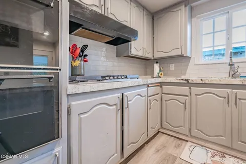 a kitchen with granite countertop a sink cabinets stainless steel appliances and a window