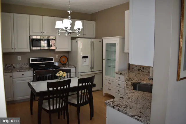 a kitchen with stainless steel appliances a table chairs and a refrigerator