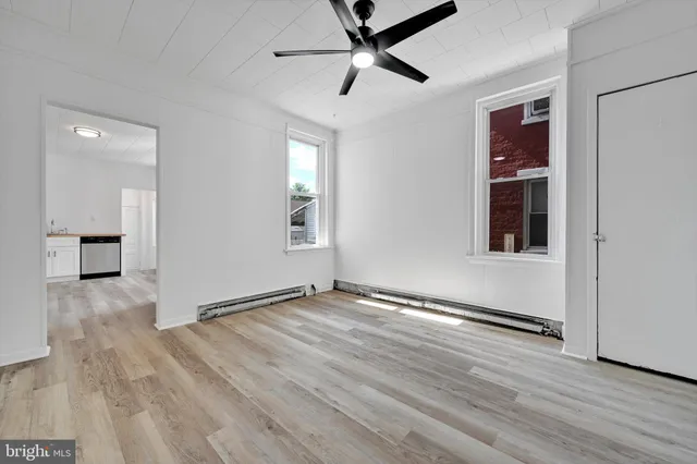 an empty room with wooden floor and windows