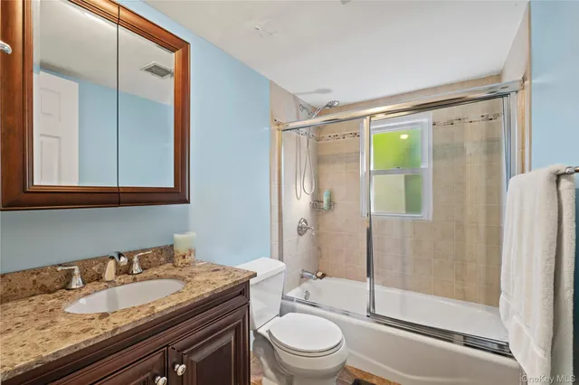 a bathroom with a granite countertop sink toilet and shower