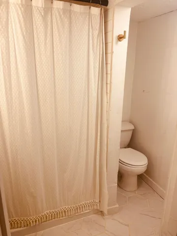 a white toilet sitting next to a white curtain