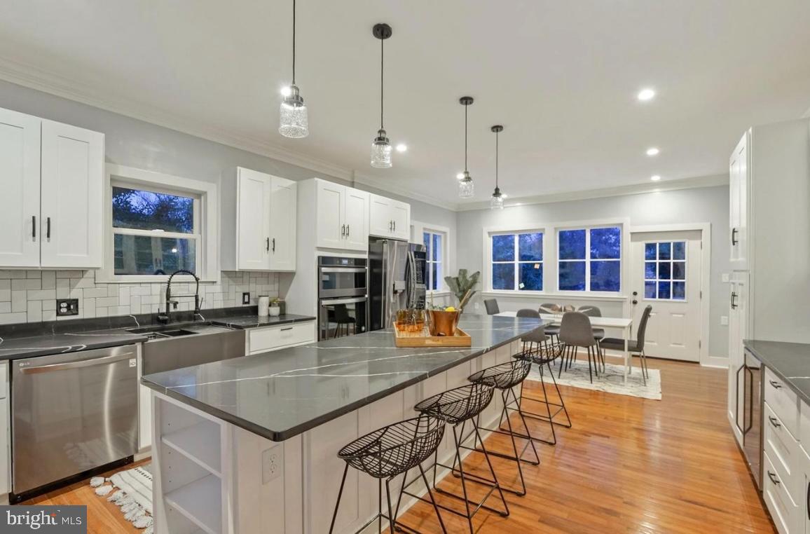 517 Cedar Street Northwest Washington, DC 20012 - Photo 1 of 1 a kitchen with stainless steel appliances granite countertop a stove a sink a microwave a dining table and chairs with wooden floor