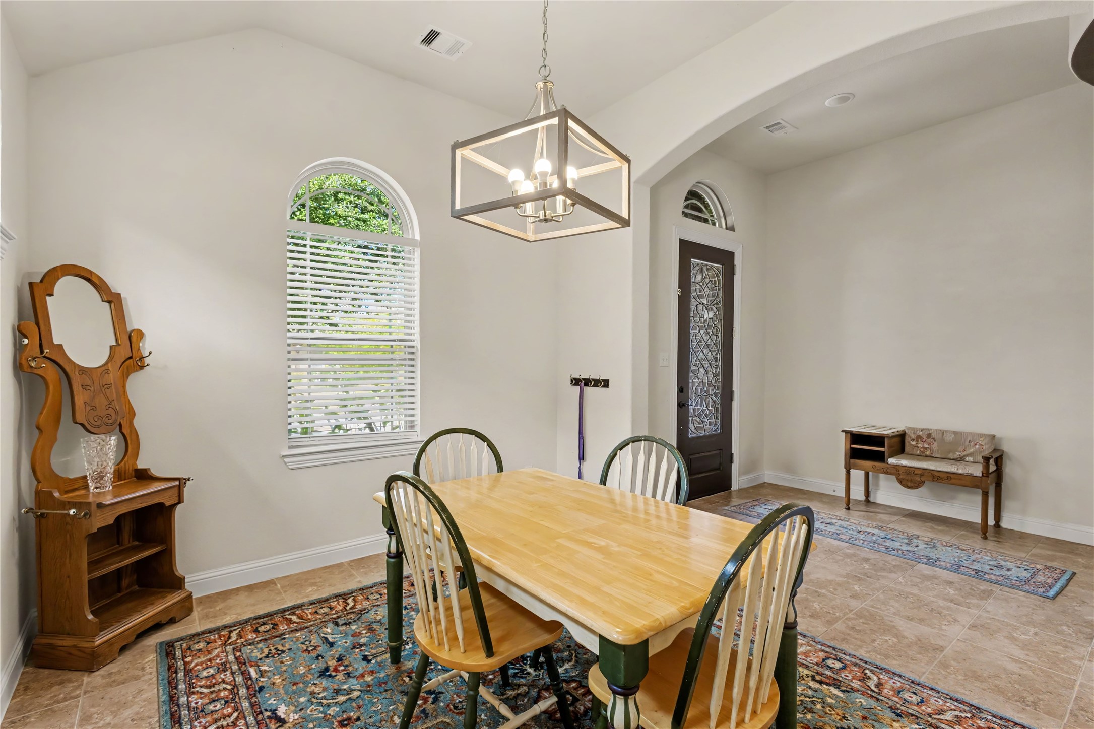 27907 Hidden Stream Drive Spring, TX 77386 - Photo 4 of 50 Bright dining area with elegant arched windows, a stylish chandelier, and a welcoming entryway featuring decorative glass.