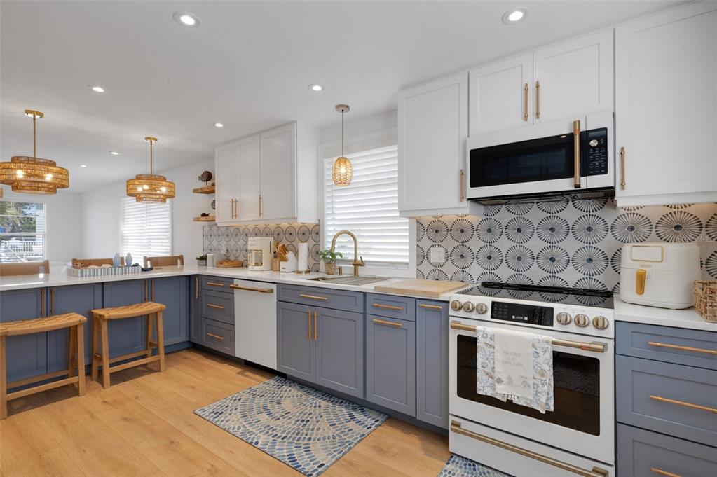 4360 Chatham Drive, Unit 108 Longboat Key, FL 34228 - Photo 18 of 56 a kitchen with stainless steel appliances granite countertop a stove top oven a sink dishwasher a microwave oven and a refrigerator