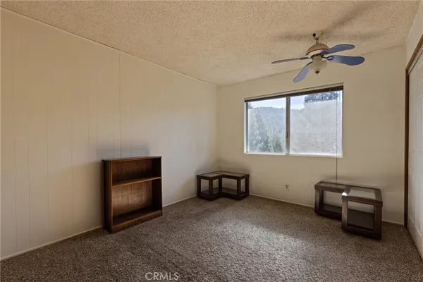 an empty room with windows and ceiling fan