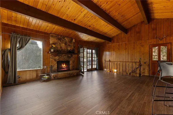 a view of an empty room with wooden floor fireplace and a window