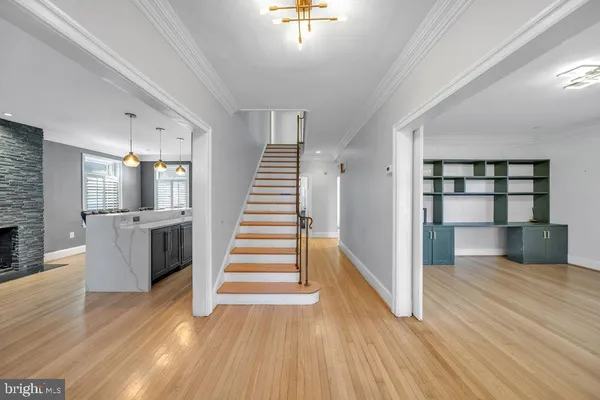 a view of an empty room with wooden floor and a kitchen