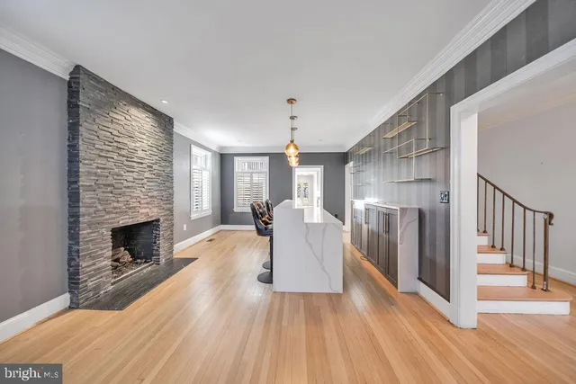 a view of an empty room with kitchen and window