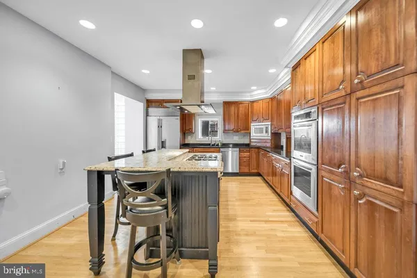 a kitchen with stainless steel appliances kitchen island granite countertop a table chairs in it and wooden floors