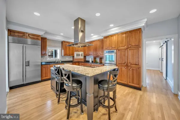 a kitchen with stainless steel appliances a dining table chairs and wooden floor