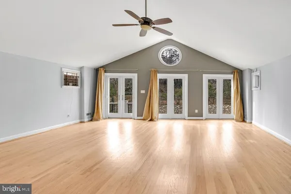 a view of an empty room with a window and wooden floor