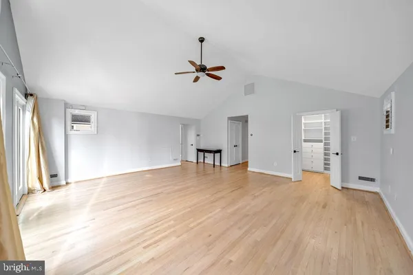 a view of empty room with wooden floor and ceiling fan