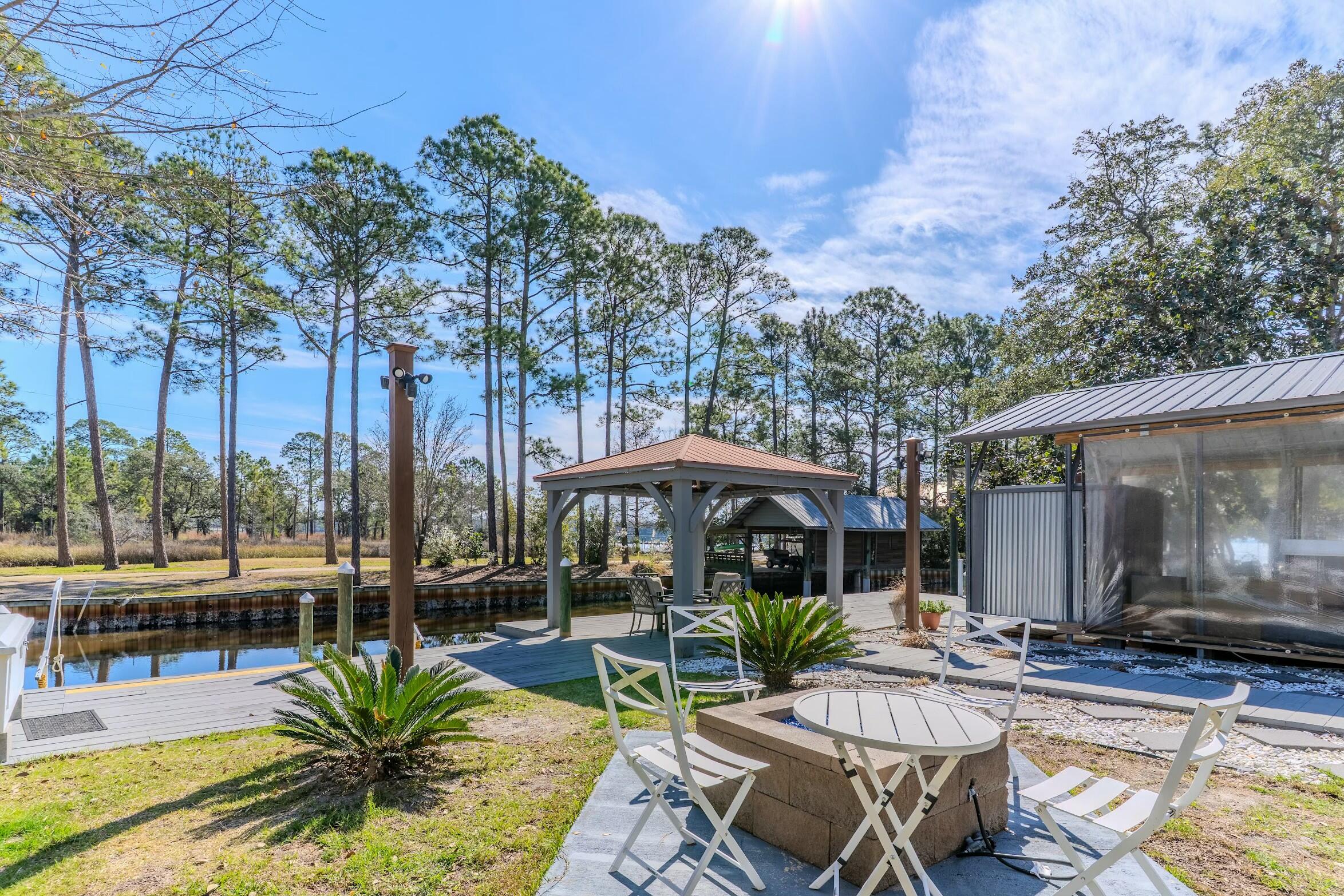 175 Ruth Road Freeport, FL 32439 - Photo 33 of 69 a view of a patio with a dining table and chairs under an umbrella with a fire pit