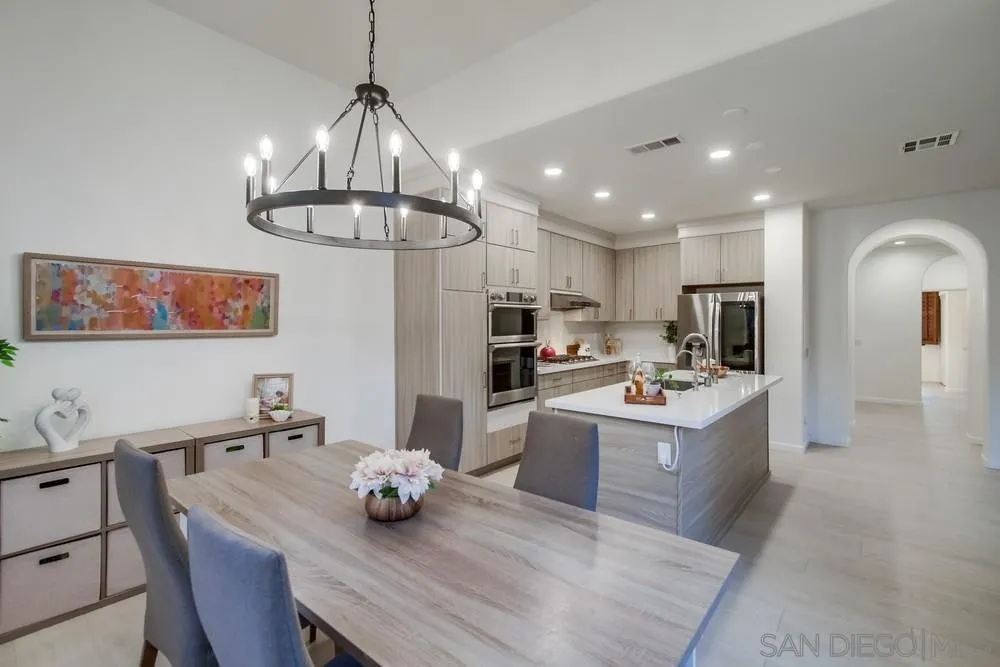 13477 Sydney Rae Place San Diego, CA 92129 - Photo 18 of 73 a kitchen with stainless steel appliances kitchen island granite countertop a table chairs and a refrigerator