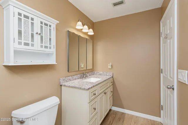 a bathroom with a granite countertop sink a toilet and a mirror