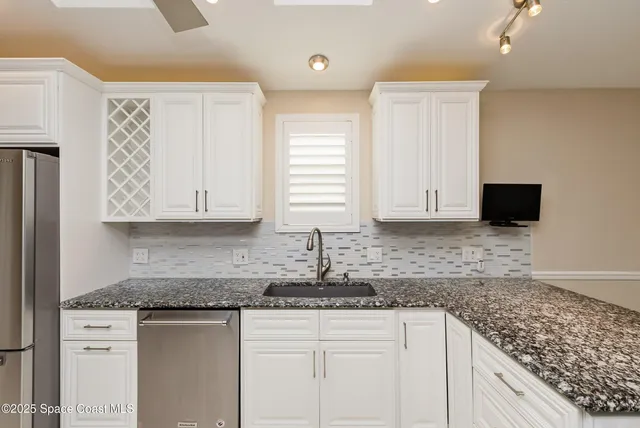 a kitchen with granite countertop a sink and white cabinets