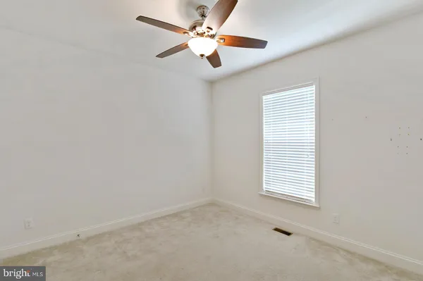 an empty room with a window and a ceiling fan