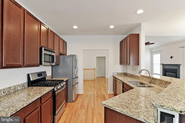a kitchen with stainless steel appliances granite countertop a sink stove microwave and refrigerator