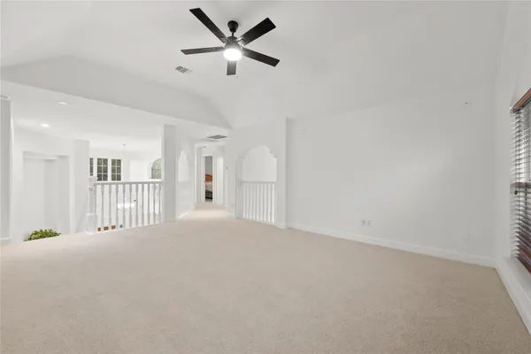 an empty room with chandelier fan and windows