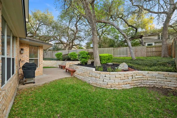 a view of a patio with table and chairs potted plants and large tree