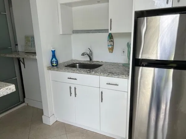 a kitchen with granite countertop a sink and a refrigerator