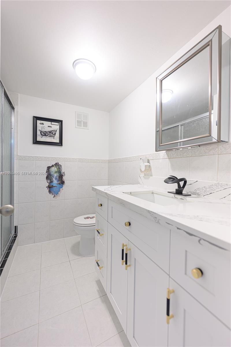 6195 Rock Island Road, Unit 503 Tamarac, FL 33319 - Photo 19 of 29 a bathroom with a granite countertop sink a toilet and a mirror