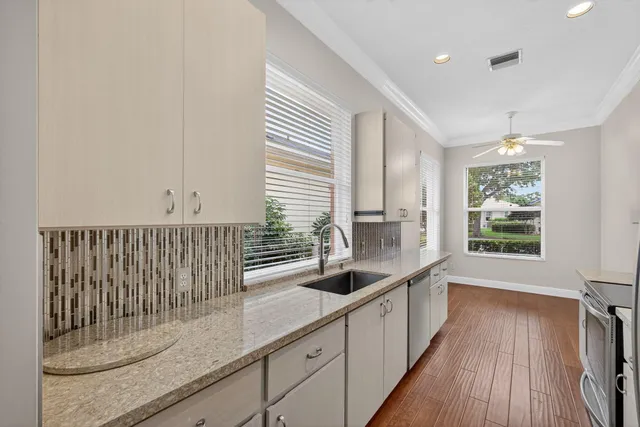 a kitchen with stainless steel appliances granite countertop a sink window and cabinets