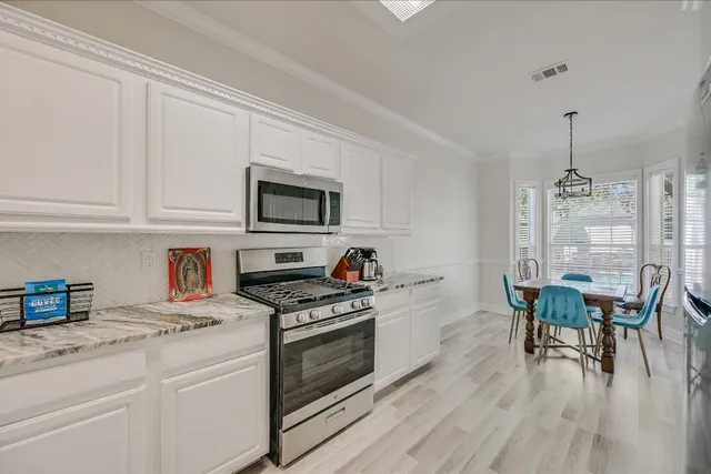 a kitchen with stainless steel appliances a stove a sink dishwasher a microwave oven with cabinets and wooden floor