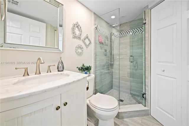 a bathroom with a shower sink vanity mirror and toilet