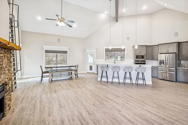 a kitchen with stainless steel appliances granite countertop a sink a stove a refrigerator cabinets and chairs