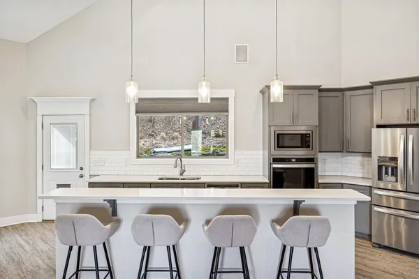 a large white kitchen with granite countertop a sink dishwasher a dining table and chairs with wooden floor