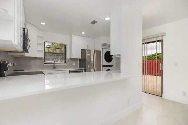a large white kitchen with lots of counter space a sink and appliances