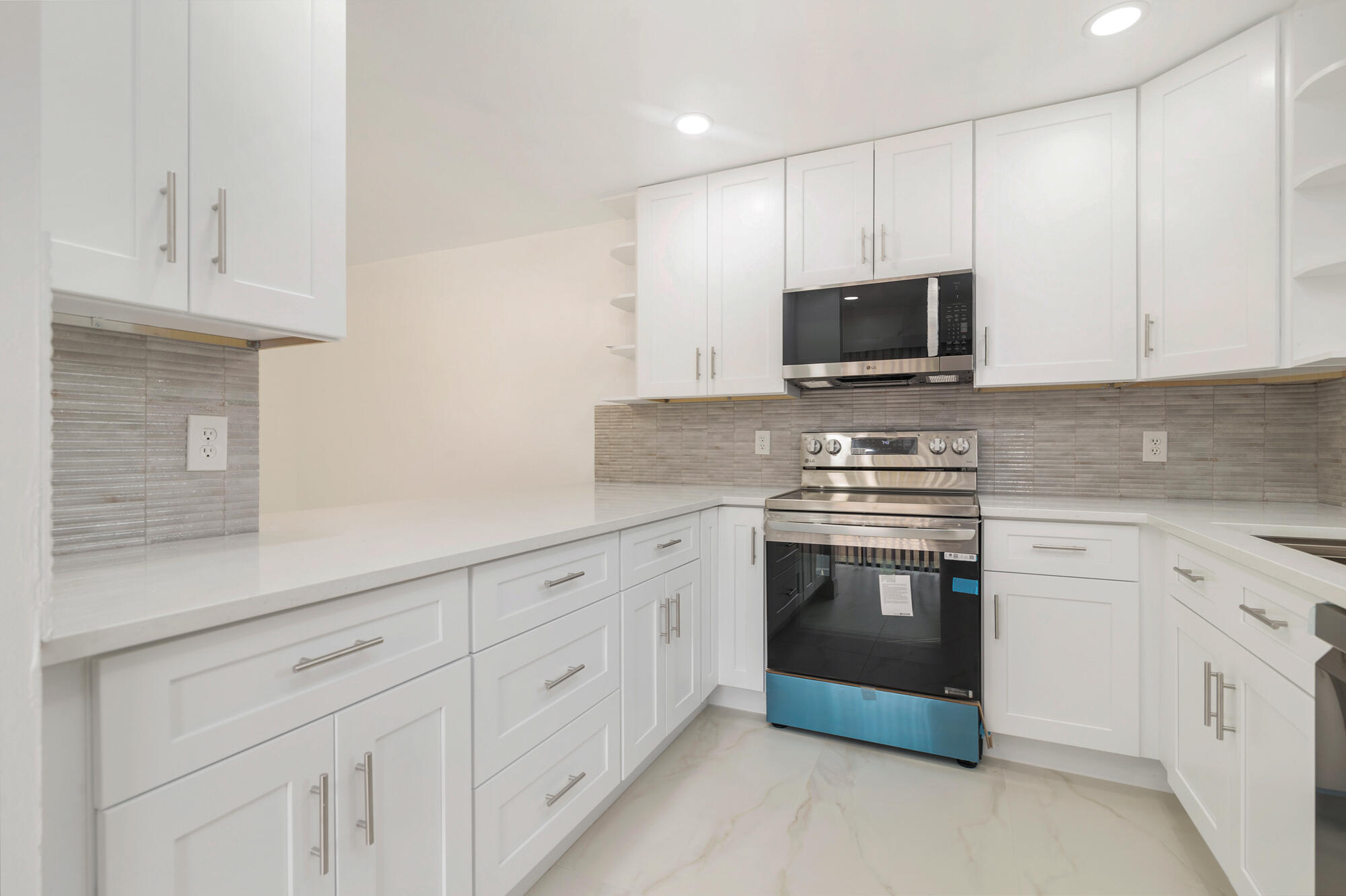 326 Jupiter Lakes Boulevard, Unit 2310B Jupiter, FL 33458 - Photo 13 of 48 a kitchen with granite countertop white cabinets stainless steel appliances and sink