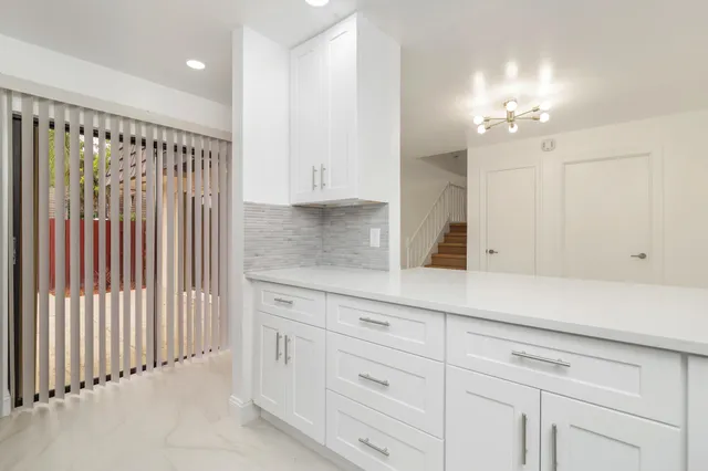 a kitchen with white cabinets and sink