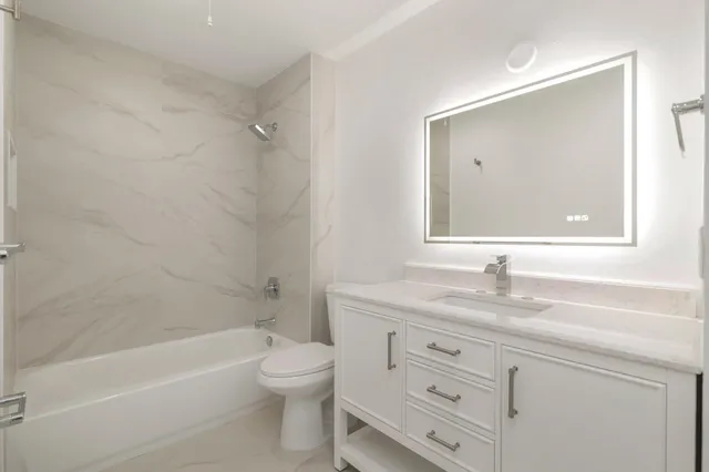 a bathroom with a granite countertop sink a toilet and bathtub