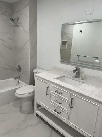 a bathroom with a granite countertop toilet sink and mirror