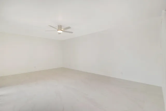an empty room with a ceiling fan and a window