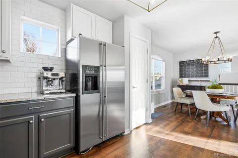 a kitchen with stainless steel appliances a refrigerator a sink a dining table and chairs