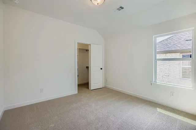 a view of an empty room with closet and a window